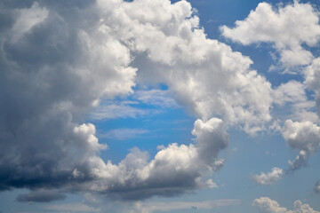 A white cloud with a round opening in the blue sky close-up, a view among clouds high in the sky...