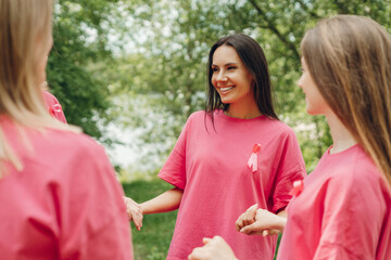Women wearing pink ribbons holding hands supporting breast cancer awareness