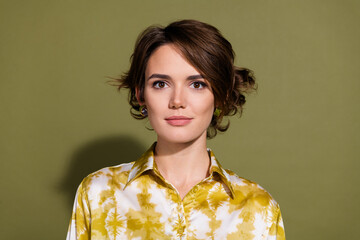Confident young businesswoman with brunette hair wearing elegant blouse against khaki background.