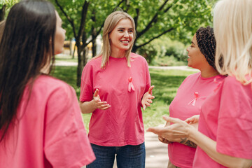 Volunteers wearing pink ribbon discussing breast cancer awareness in park