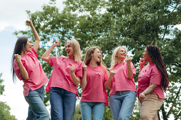 Cheerful women celebrating breast cancer awareness in park