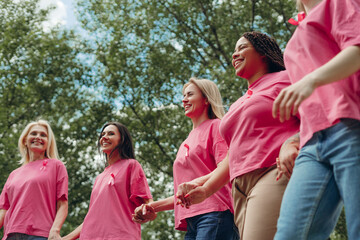 Women holding hands and wearing pink ribbons are walking for breast cancer awareness