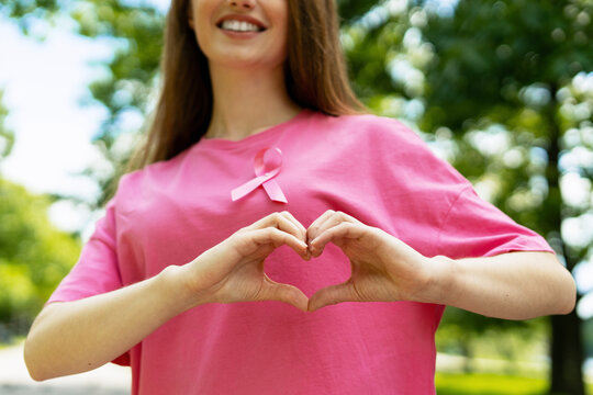 Woman making heart shape with hands for breast cancer awareness - Powered by Adobe