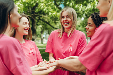 Volunteers wearing pink ribbons joining hands for breast cancer awareness