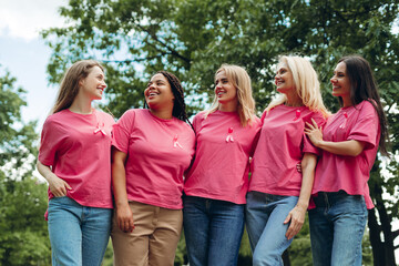 Smiling women wearing pink ribbons supporting breast cancer awareness in park