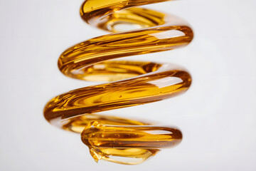 Fototapeta premium Spiraling stream of golden viscous liquid with transparent reflections.