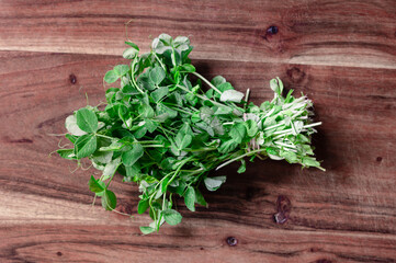 A fresh bunch of pea sprouts on a wood cutting board
