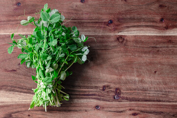 A bunch of pea sprouts on a wood cutting board with copy space to the right