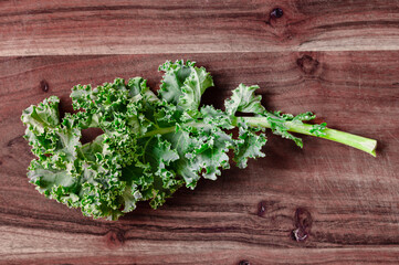 A single green kale leaf on a wood cutting board