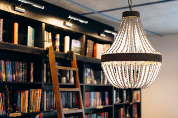 Vintage chandelier in an old bookstore with a wooden ladder in the background.