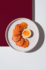 Rodajas de naranja sanguina sobre un plato blanco con fondo blanco y granate. Vista superior