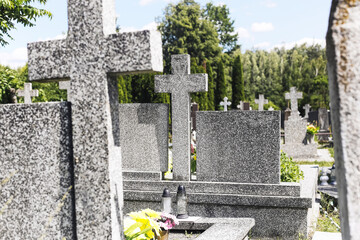Cemetery with granite tombstones. Rows of graves with stone crosses. Peaceful resting place under blue sky. Memory and respect for the dead. Traditional graveyard view with flowers and candles.