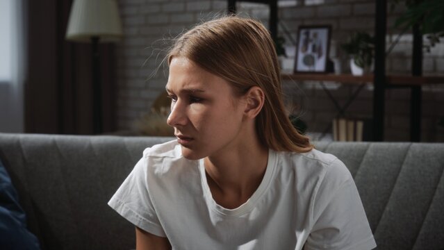 Young Woman in Thoughtful Pose on Comfortable Sofa