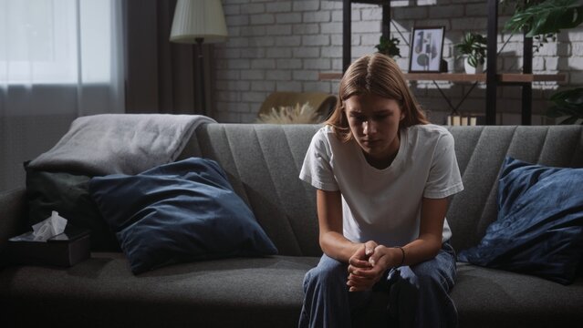 Young Woman Sitting on Sofa Deep in Thought at Home
