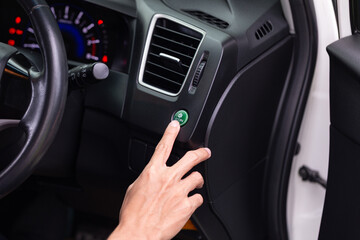Close-up of a hand pressing the ECON button on a car dashboard, indicating activation of eco mode....