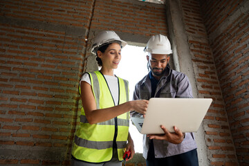 Two Engineer builder. Foreman use notebook computer and walkie talkie working in construction site.