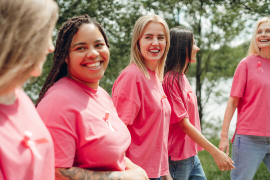 Diverse women walking together showing pink ribbons for breast cancer awareness