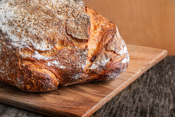 Freshly baked artisan bread resting on a wooden cutting board in a rustic kitchen setting