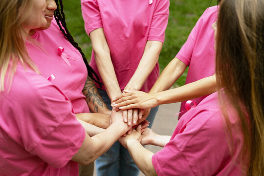 Volunteers joining hands showing support for breast cancer awareness