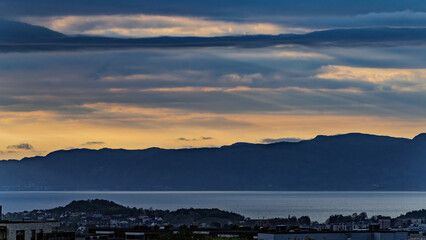 Sunset Over Urban Landscape With Mountains and Clouds in Scenic Background, Trondheim, Norway