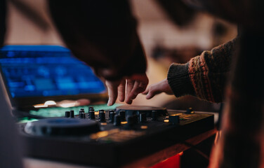 Fototapeta premium Two individuals collaborate on a DJ setup, showcasing teamwork and passion for music creation.