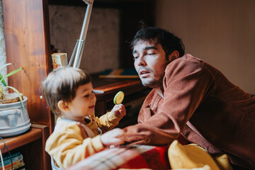 Young father engaging with his smiling toddler in a warm, comfortable home setting, emphasizing happy family moments and togetherness.