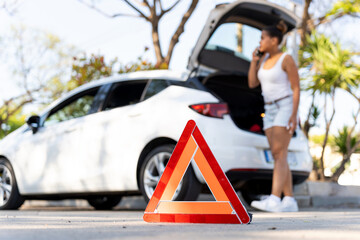 Warning triangle signalling road breakdown or car accident with driver calling for assistance