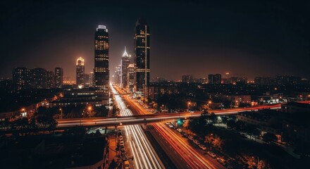 Obraz premium Cityscape at night with tall buildings and long exposure of car lights on the streets below
