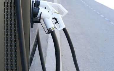 EV charging station in city close-up, road in background. Convenience and environmental benefits of electric vehicles, alternative fuel, car service. Accessible car energy resource in public areas
