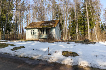 
a small, old, light blue house with a brown roof, located at the edge of the forest, and in front...