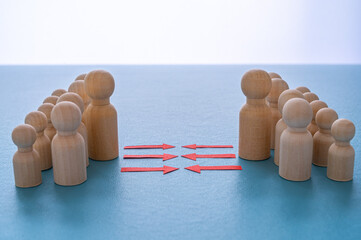 Concept of conflict I war between people or groups. Wooden figures gathered in two groups facing each other.