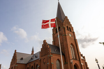 Nykobing Mors, Denmark  The Nykoping Mors Church, the Sankt Clemens Kirke,  and a Danish flag. © Alexander