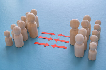Concept of conflict I war between people or groups. Wooden figures gathered in two groups facing each other.