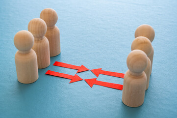 Concept of conflict I war between people or groups. Wooden figures gathered in two groups facing each other.