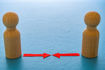 Concept of conflict I war between people or groups. Wooden figures gathered in two groups facing each other.