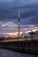 The famous Television Tower and the river Spree with a motion blurred commuter train in Berlin at twilight