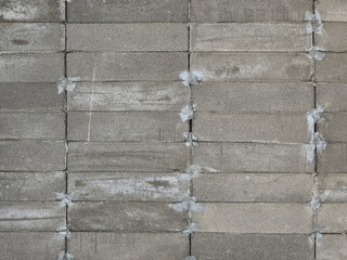 Textured gray concrete blocks arranged in uniform pattern, showcasing rough surface and mortar joints. This captures industrial aesthetic of masonry work