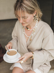 stylish girl, blonde holding cup of coffee, warming drink, good start of day, coffee aroma, linen clothes, beige color scheme, stylish expensive accessories