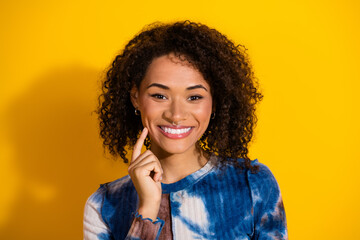 Portrait of a cheerful young woman in a stylish top against a vibrant yellow background.