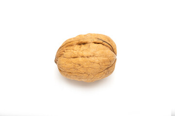 A whole walnut with a rough, brown shell. The walnut is placed on a white background, 