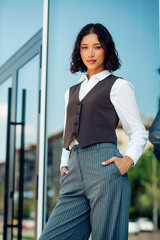 Confident young businesswoman in stylish formalwear posing outdoors in an urban environment on a...