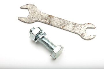 A metal wrench and a bolt with a nut are placed on a white background. The wrench is slightly rusted, while the bolt is shiny and new.