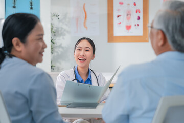 Asian doctor in uniform attentively assists a senior couple with medical paperwork in a hospital area, explaining health records and test results with care and professionalis senior health