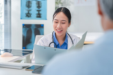 Asian doctor in uniform attentively assists a senior couple with medical paperwork in a hospital area, explaining health records and test results with care and professionalis senior health