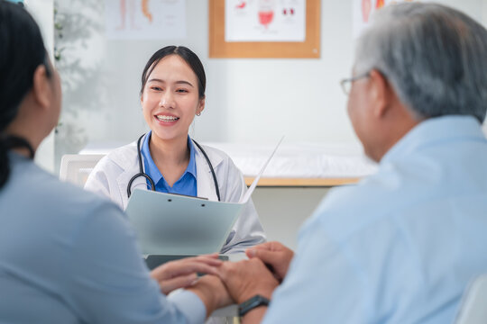 Asian doctor in uniform attentively assists a senior couple with medical paperwork in a hospital area, explaining health records and test results with care and professionalis senior health