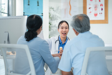 Asian doctor in uniform attentively assists a senior couple with medical paperwork in a hospital area, explaining health records and test results with care and professionalis senior health