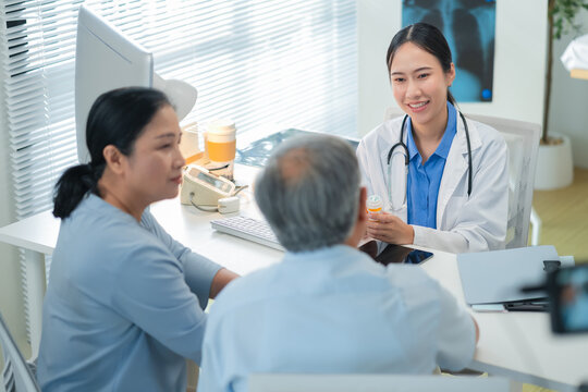 Asian doctor in uniform attentively assists a senior couple with medical paperwork in a hospital area, explaining health records and test results with care and professionalis senior health