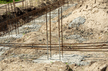 Workers are preparing a concrete foundation with steel rebar framework at a construction site under...