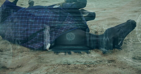 Fototapeta premium Lying face-down adult wearing plaid coat with tactical boots on desert shore with tech HUD overlays