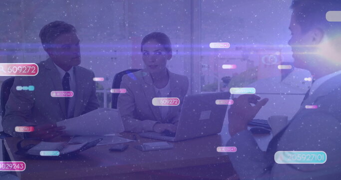 Reviewing team in suits discussing data with digital overlays on laptop and reports in meeting room